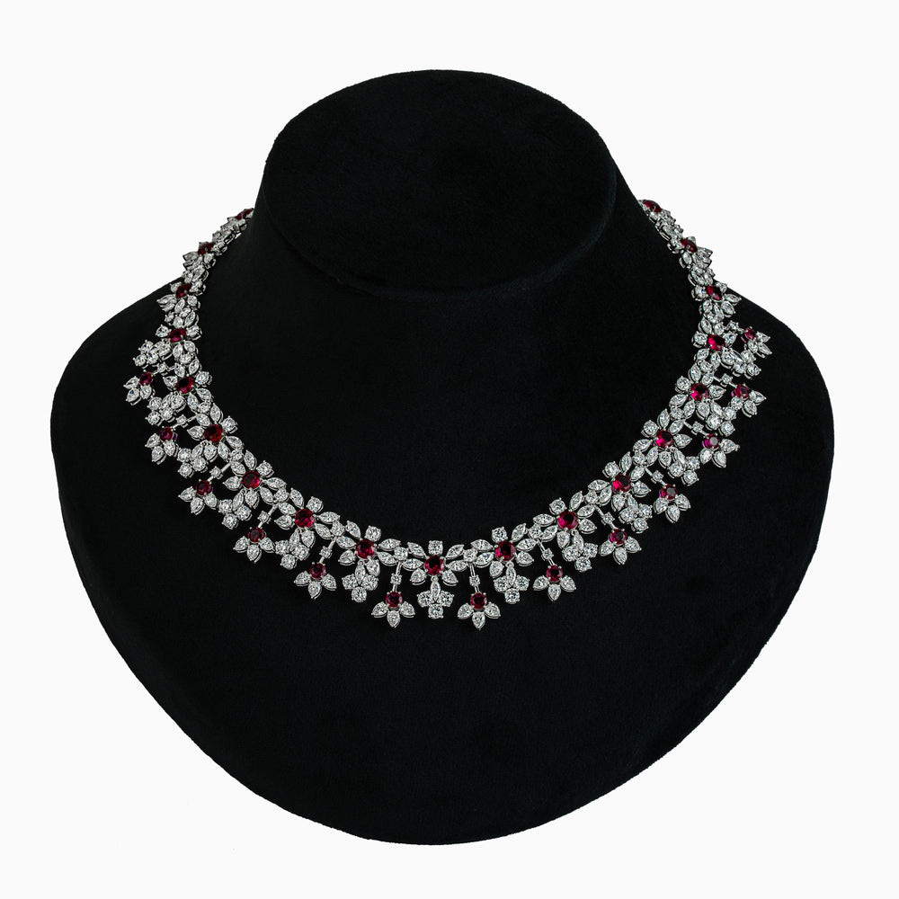 Elegant diamond necklace with ruby accents displayed on black velvet mannequin bust