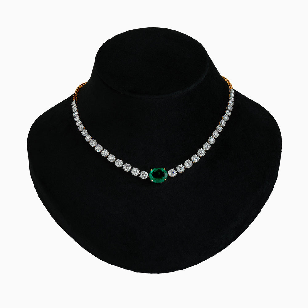 Diamond tennis necklace with emerald centerpiece on black jewelry display