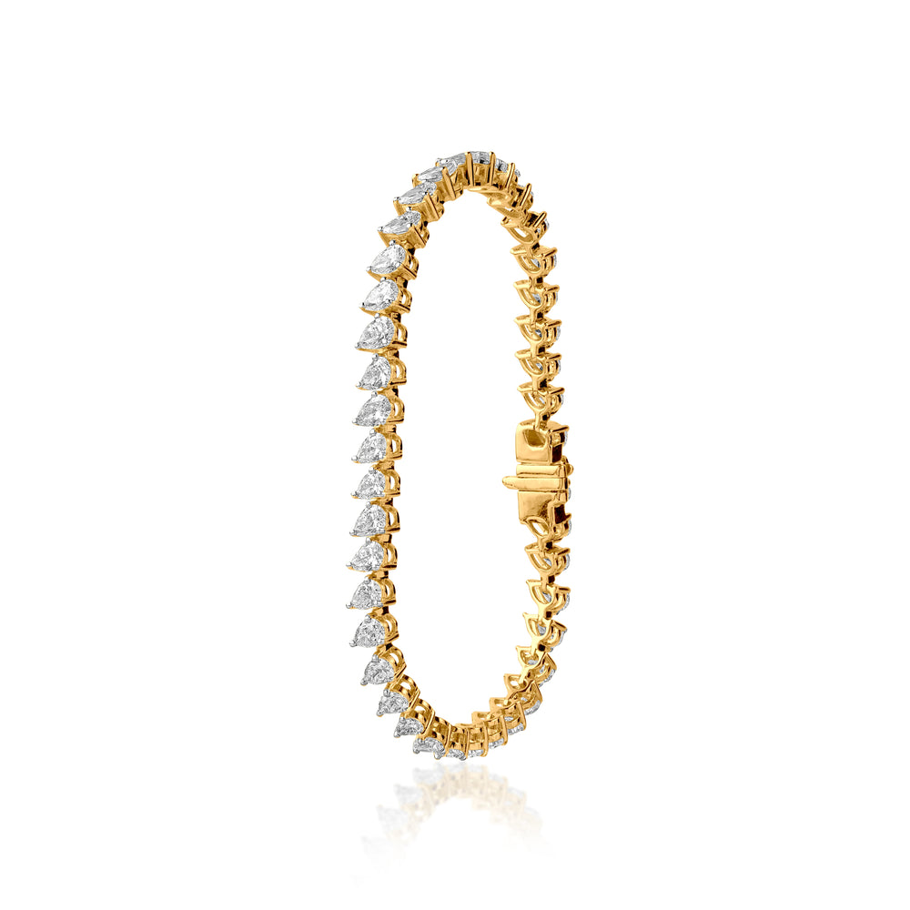 Gold tennis bracelet with pear-shaped diamonds in elegant, intricate setting