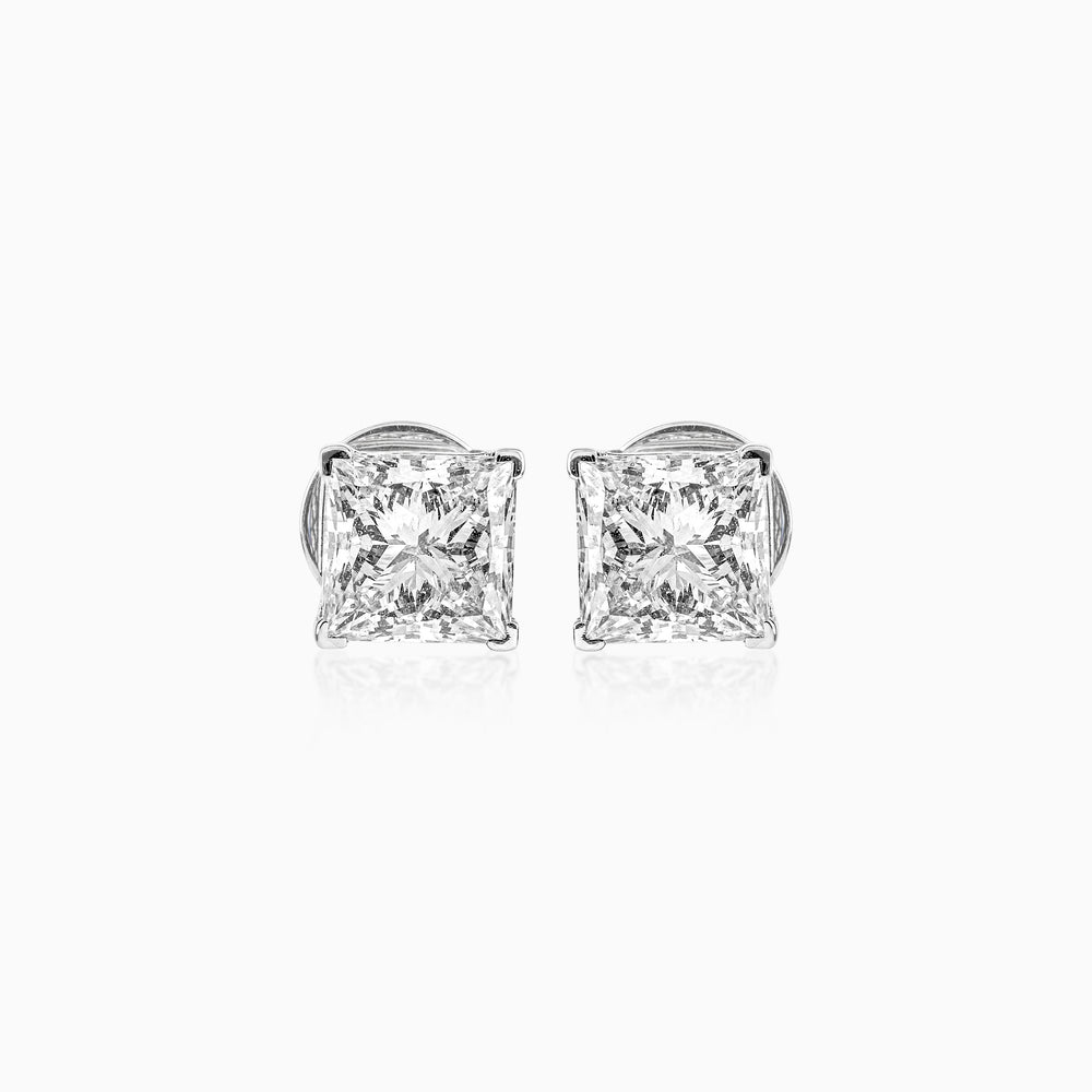 Princess-cut diamond stud earrings in silver, sparkling against white background