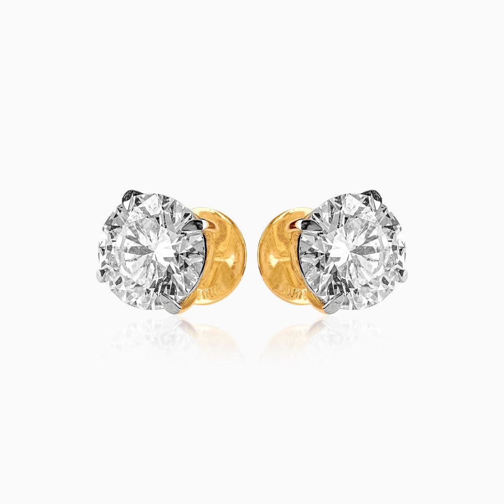 Pair of diamond stud earrings with gold backings, sparkling brilliantly against white background