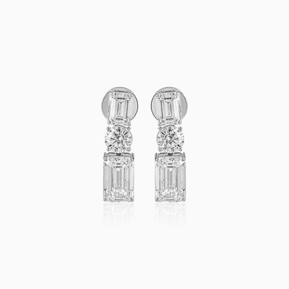 Diamond drop earrings with emerald-cut and round brilliant stones in silver setting