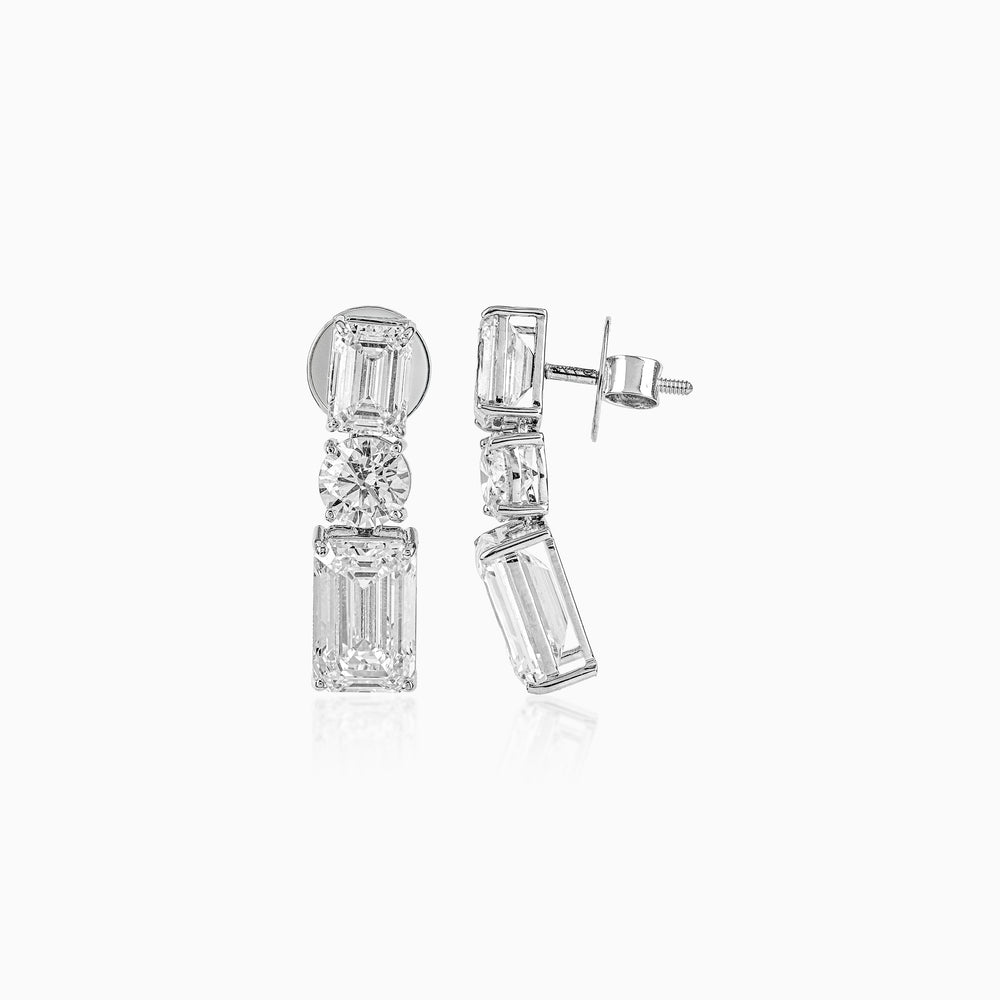 Diamond earrings with emerald-cut and round stones in geometric vertical arrangement