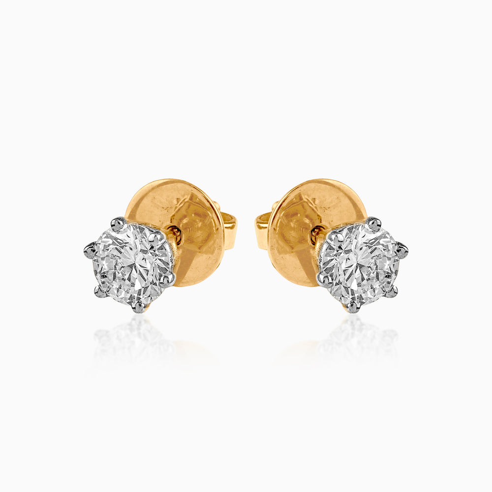 Gold stud earrings with sparkling round diamond solitaires in six-prong white gold settings.