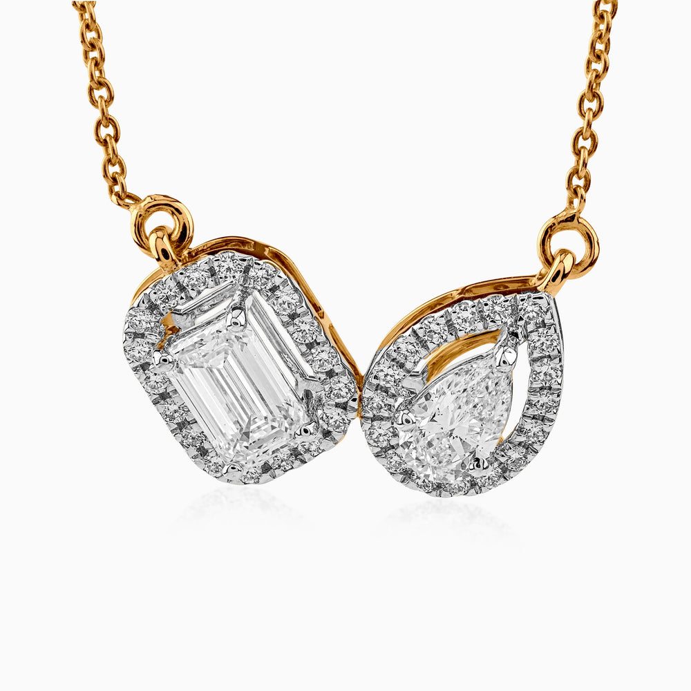 Gold necklace with two diamond pendants in emerald and pear cut, surrounded by smaller diamonds