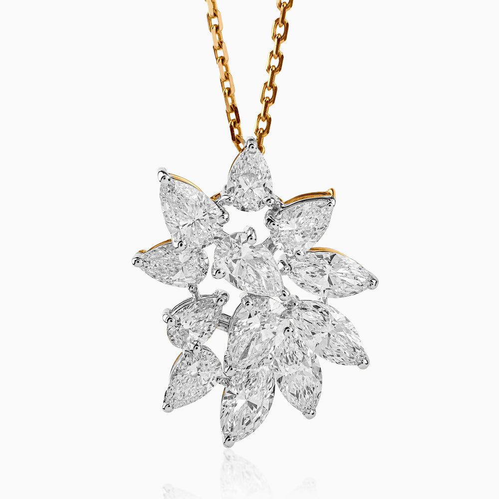 Diamond cluster pendant with pear-shaped stones on gold chain, sparkling against white background.