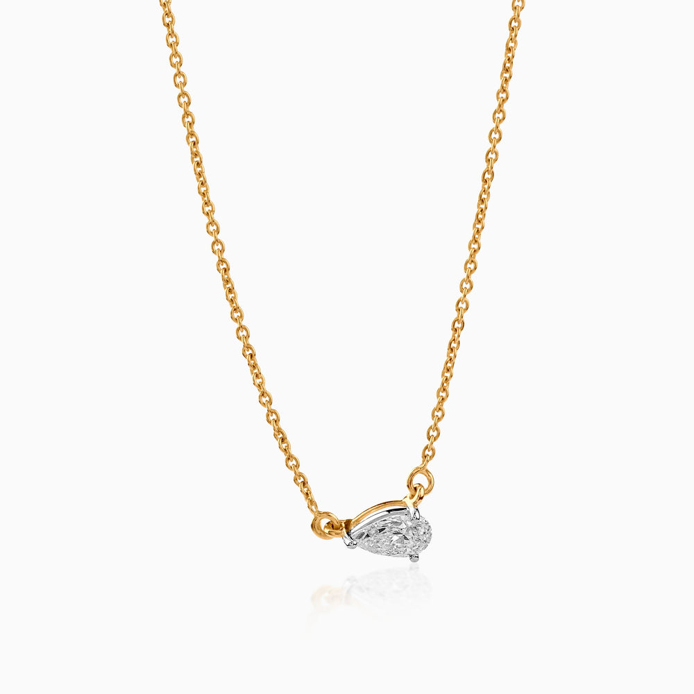 Gold chain necklace with pear-shaped diamond pendant on white background