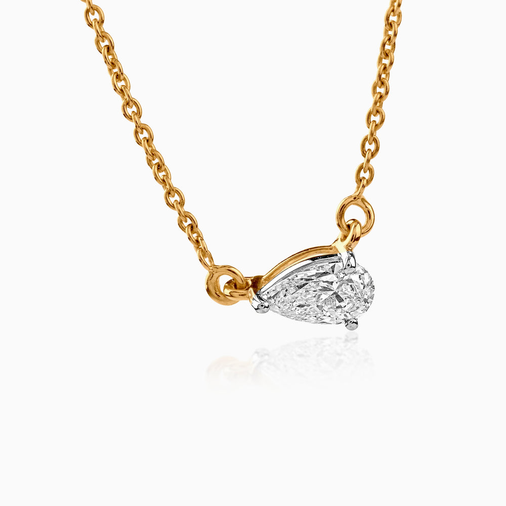 Delicate gold necklace with pear-shaped diamond pendant in white gold setting