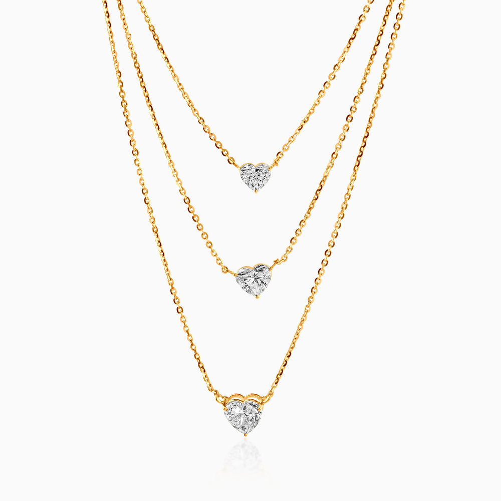 Gold layered necklace with three heart-shaped diamond pendants on delicate chains.