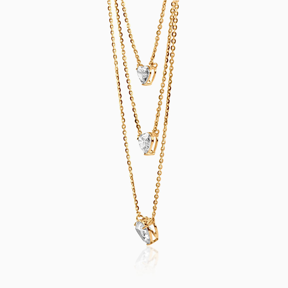 Gold layered necklace with three heart-shaped diamond pendants on delicate chains