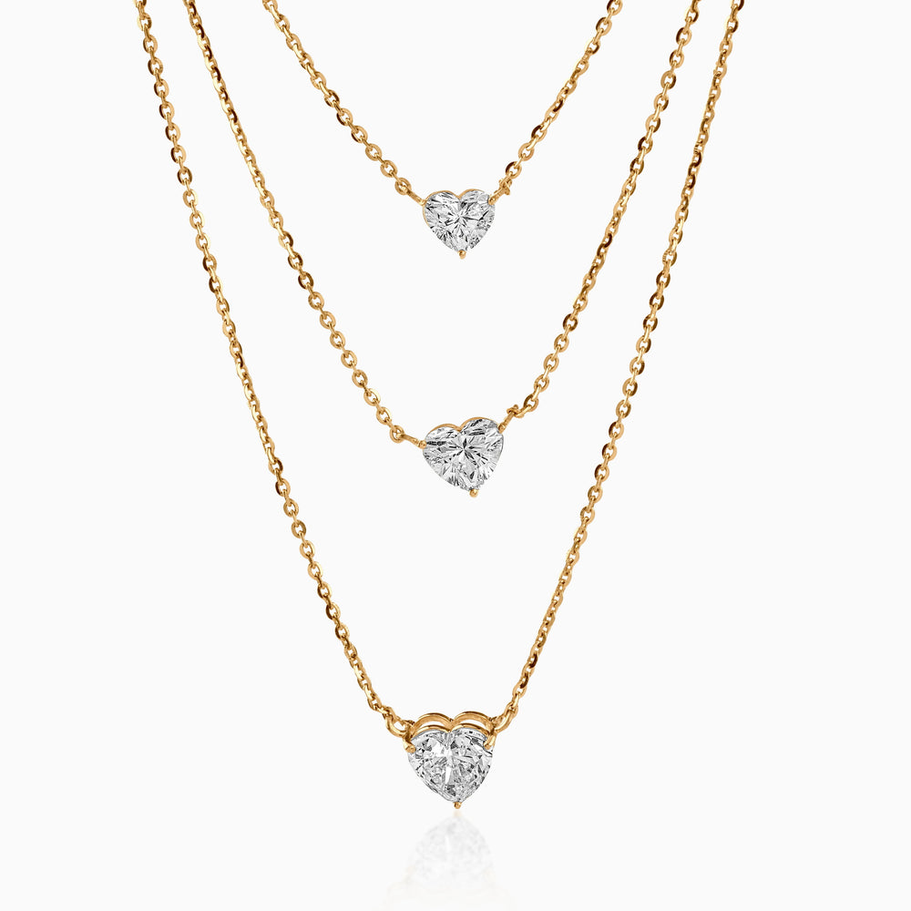 Gold necklaces with heart-shaped diamond pendants cascading at different lengths
