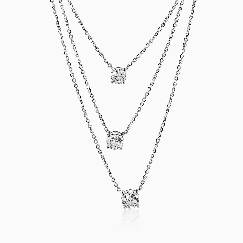 Three-strand silver necklace with round diamond pendants hanging at different lengths.