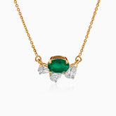 Gold necklace with emerald center stone and diamond side accents on delicate chain