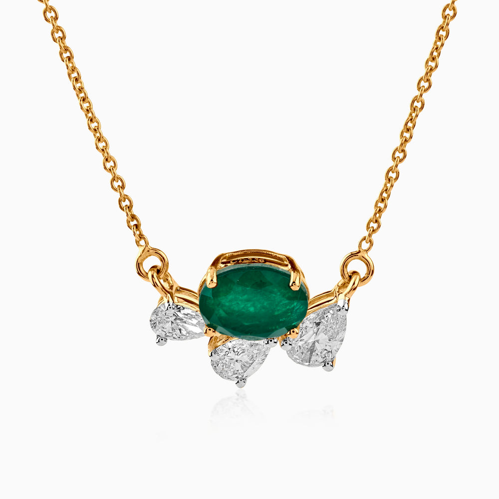 Gold necklace with emerald center stone and diamond side accents on delicate chain