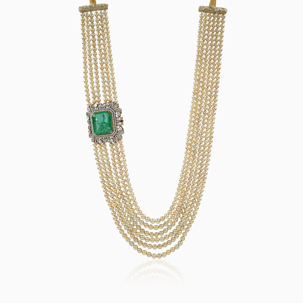Multi-strand pearl necklace with emerald and diamond-encrusted pendant clasp.