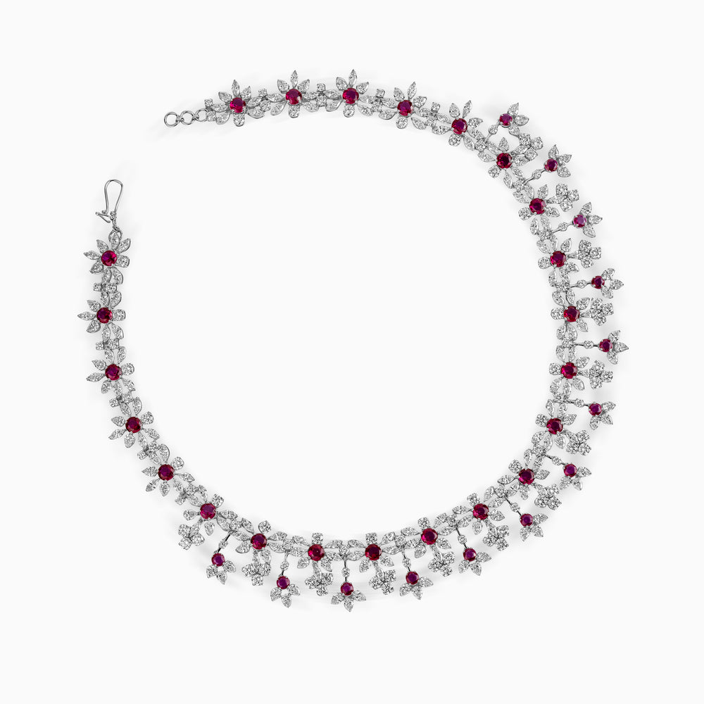 Elegant diamond and ruby necklace with floral-inspired design, curving in a graceful arc