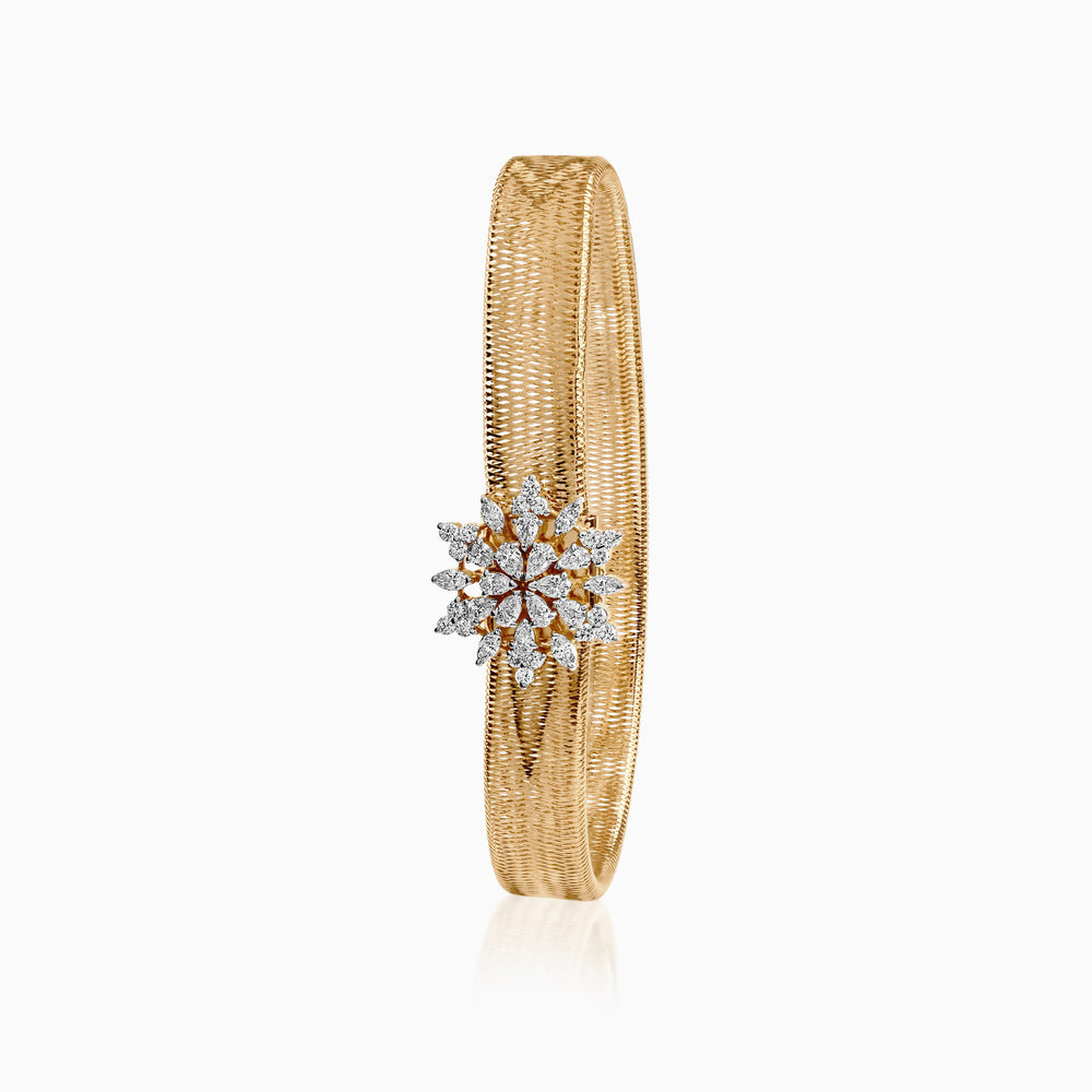 Gold woven bracelet with snowflake diamond cluster on white background