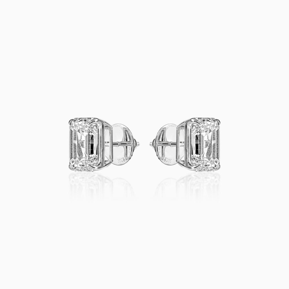Diamond stud earrings with emerald-cut stones in white gold, reflecting light