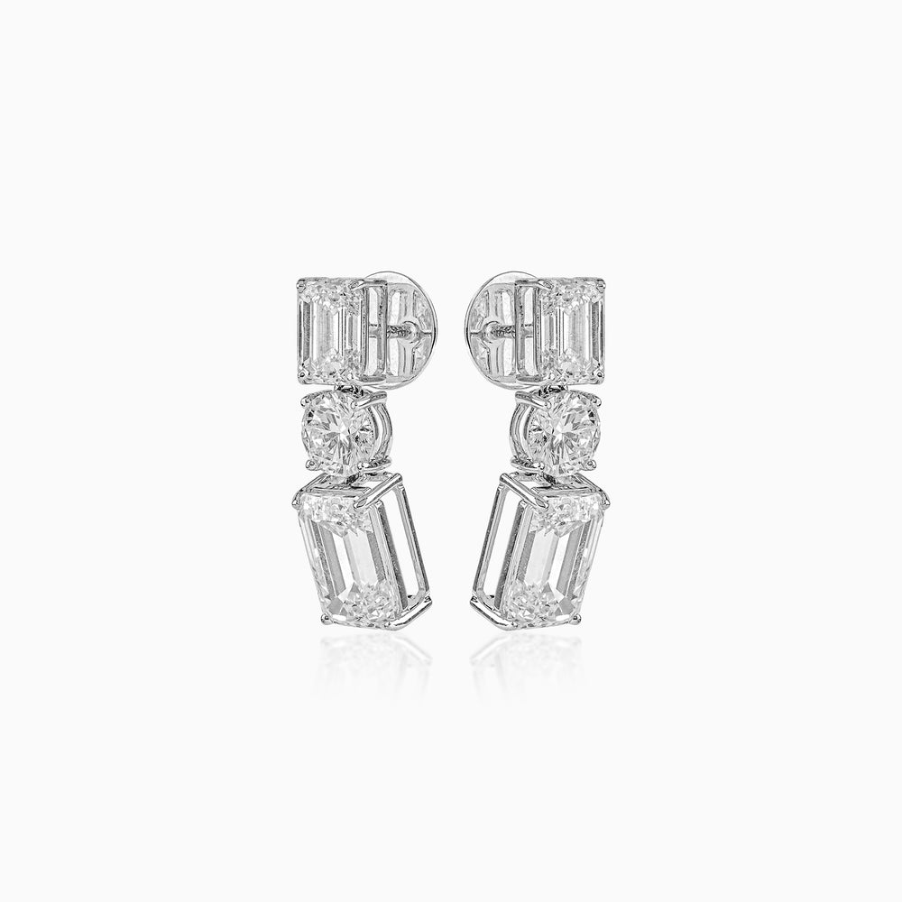 Diamond earrings with emerald-cut stones in geometric three-tier design on white background