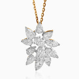 Diamond cluster pendant with pear-shaped stones on gold chain, sparkling against white background.