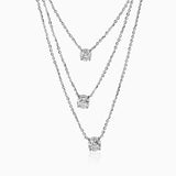 Three-strand silver necklace with round diamond pendants hanging at different lengths.