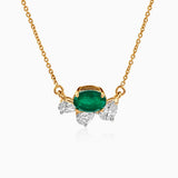 Gold necklace with emerald center stone and diamond side accents on delicate chain