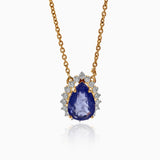 Gold necklace with teardrop sapphire pendant, surrounded by diamond halo on delicate chain