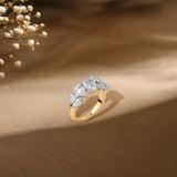 Gold ring with five pear-shaped diamonds, styled with delicate white flowers in soft background.
