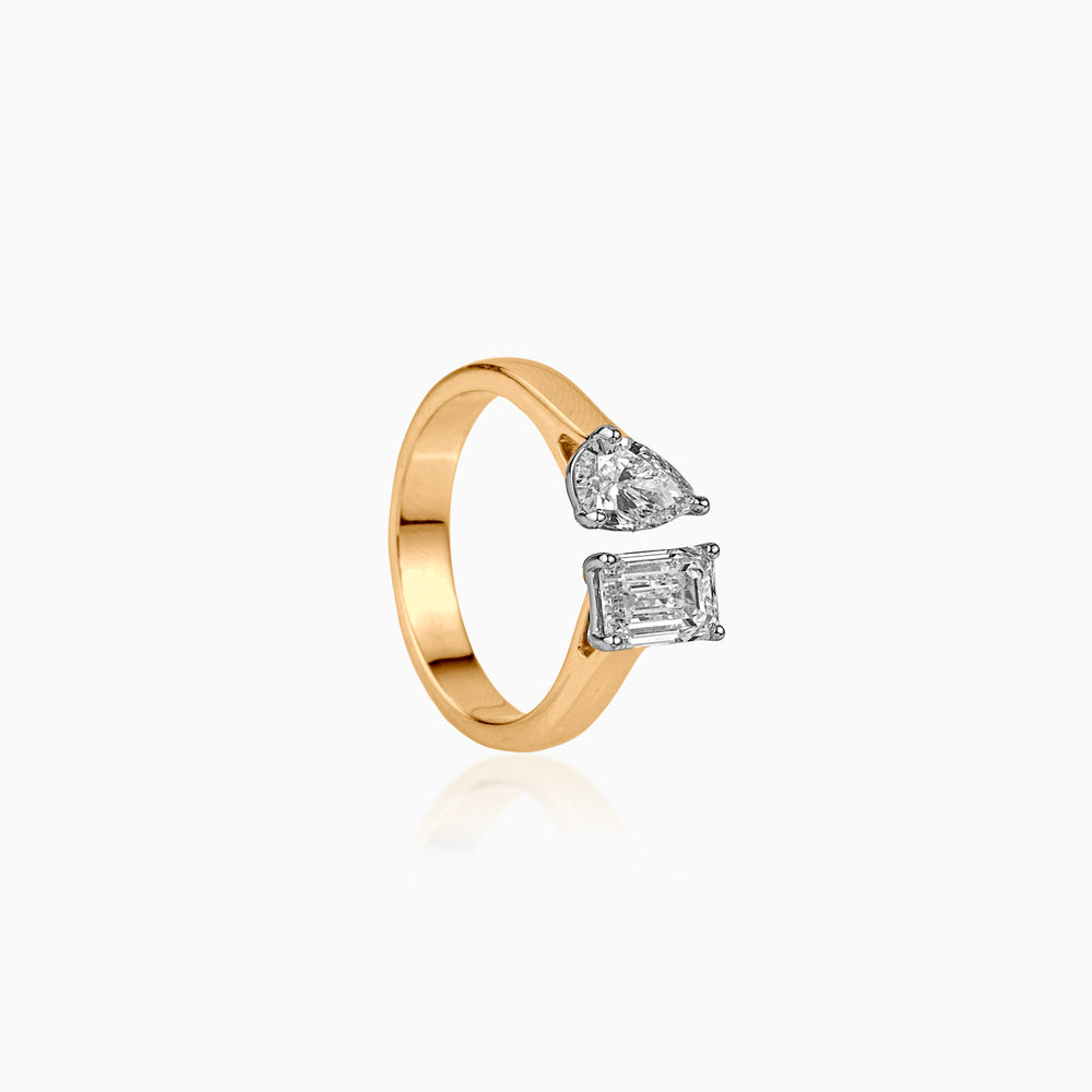 Gold ring with open design featuring pear and emerald-cut diamonds in white setting