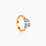 Gold ring with open design featuring pear and emerald-cut diamonds in white setting