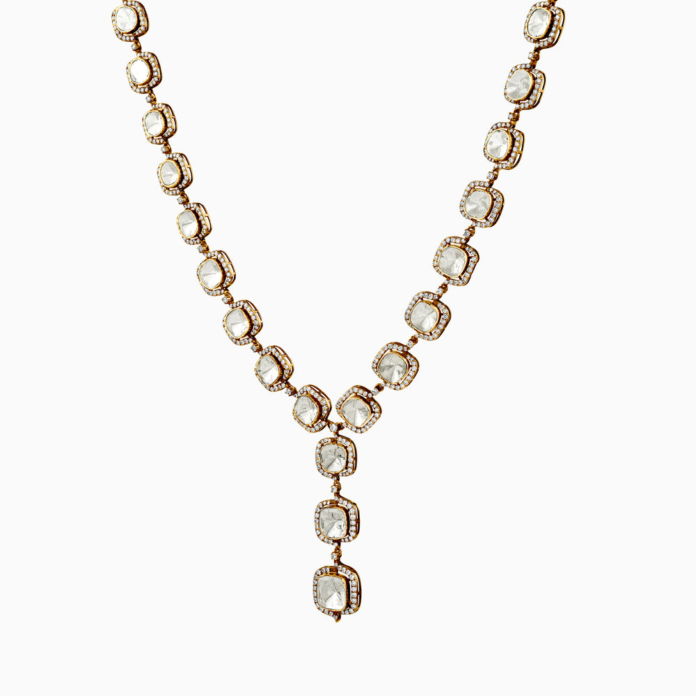 Gold necklace with square diamond-like stones in Y-shaped elegant design on white background