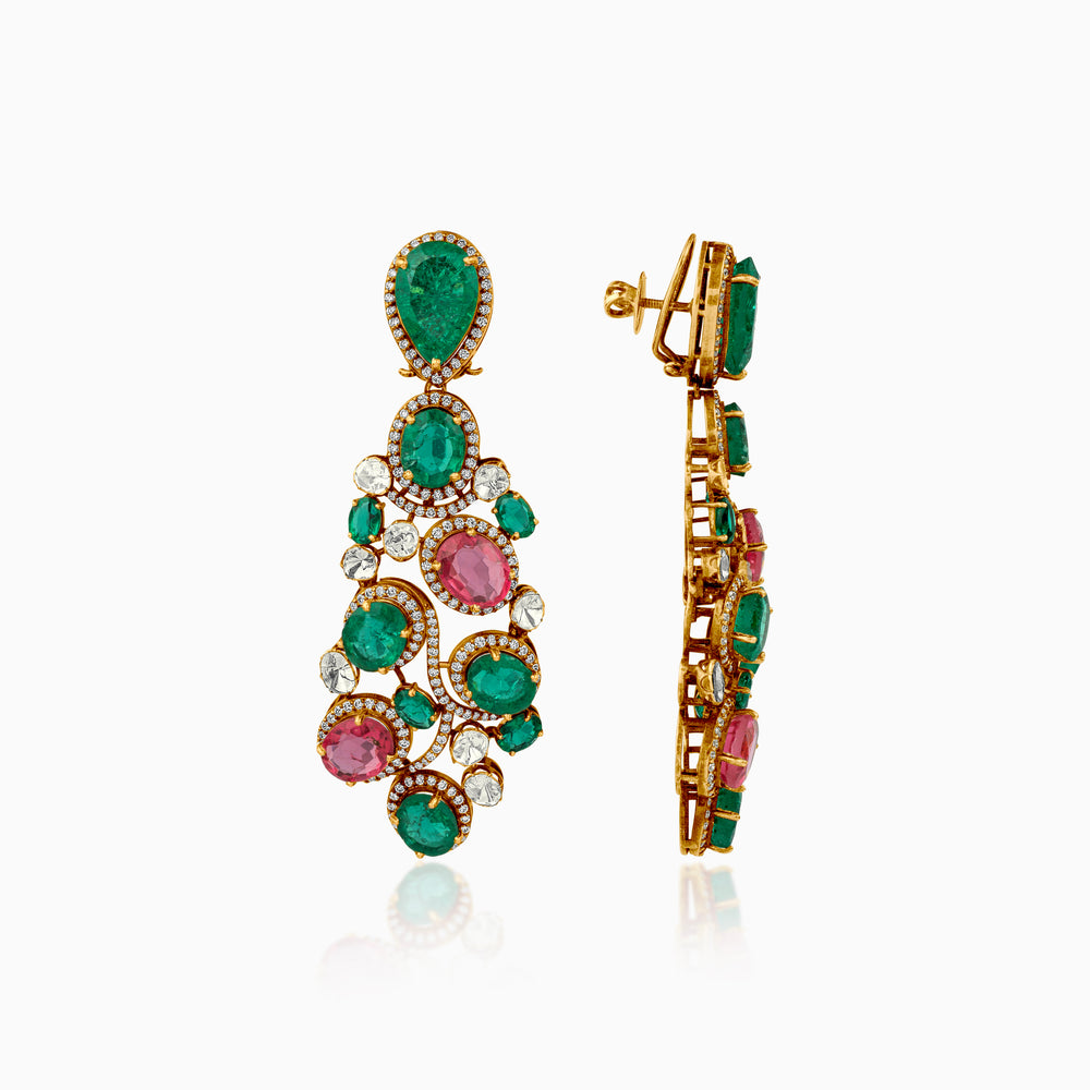 Intricate gold earrings with emerald green and pink gemstones, surrounded by diamond halos.